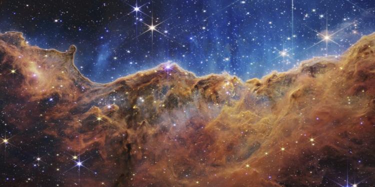 This image released by NASA on Tuesday, July 12, 2022, shows the edge of a nearby, young, star-forming region NGC 3324 in the Carina Nebula. Captured in infrared light by the Near-Infrared Camera (NIRCam) on the James Webb Space Telescope, this image reveals previously obscured areas of star birth, according to NASA. (NASA, ESA, CSA, and STScI via AP)