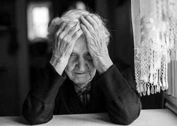 An elderly woman sitting at the table in a depressed state, black and white photo.