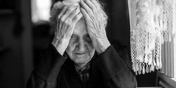An elderly woman sitting at the table in a depressed state, black and white photo.