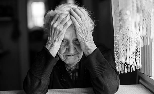 An elderly woman sitting at the table in a depressed state, black and white photo.