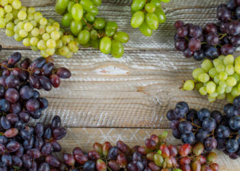 Ripe grapes on wooden background, flat lay.
