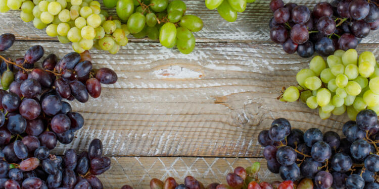 Ripe grapes on wooden background, flat lay.